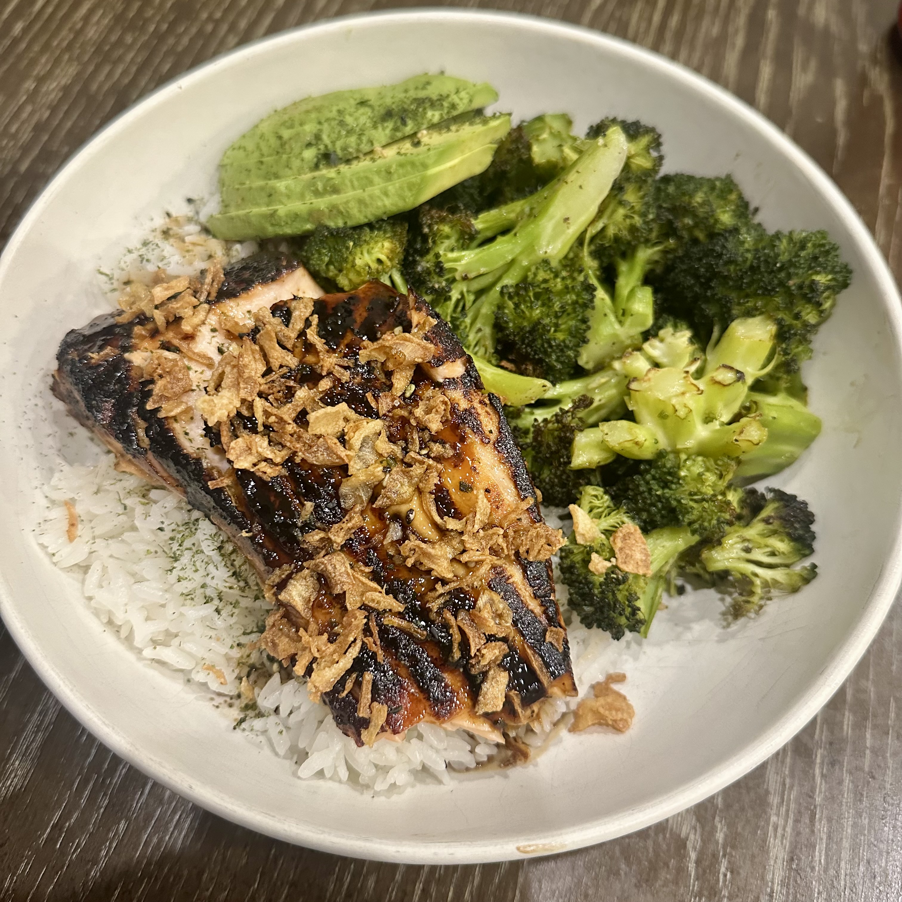 Slightly burnt salmon on a bed of rice and broccoli, topped with fried onion and furikake