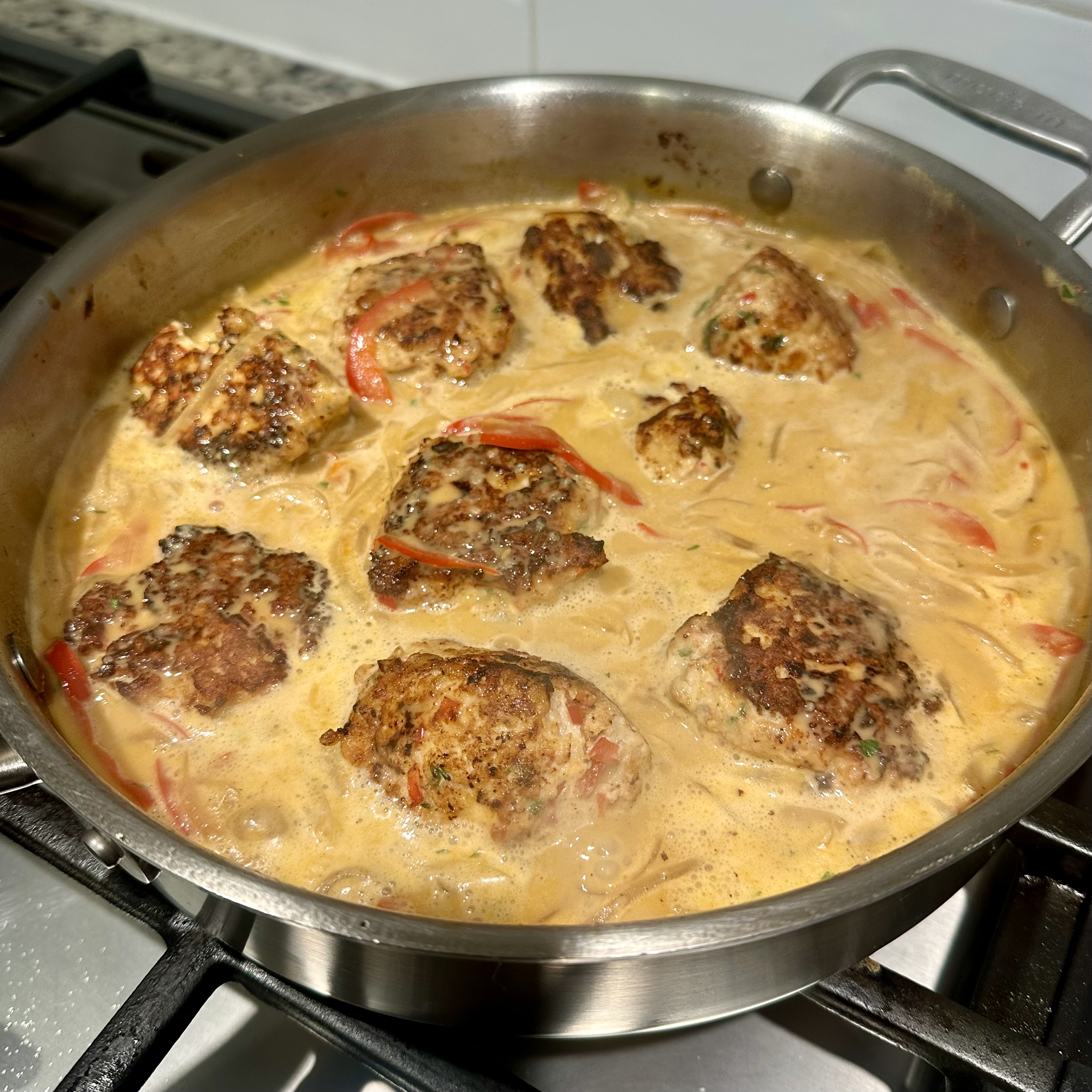 Pan of chicken meatballs cooking in a red curry